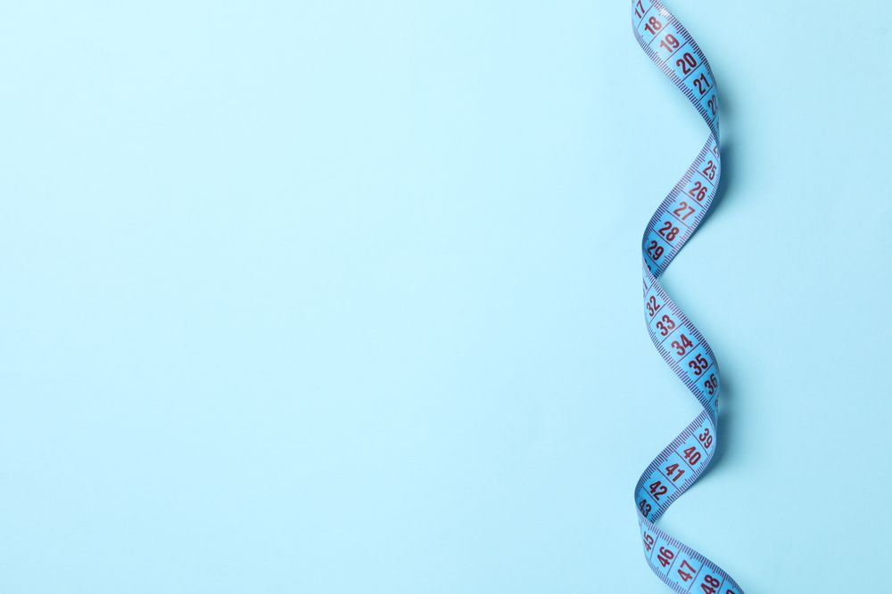 Measuring tape on blue background. Weight loss concept