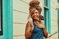 Laughing Black female snacking on an ice cream cone in the sun