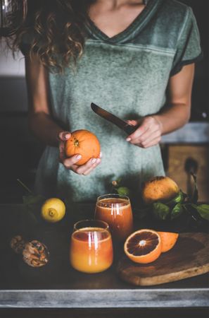 Woman holding knife with freshly squeezed blood orange juice