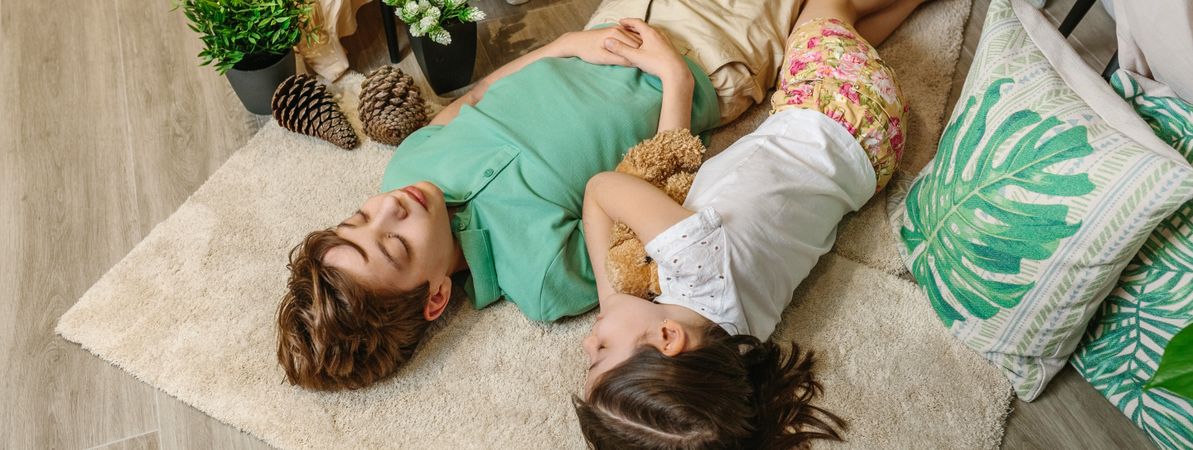 Banner of two children sleeping lying over rug in cozy warm and playful atmosphere at home.