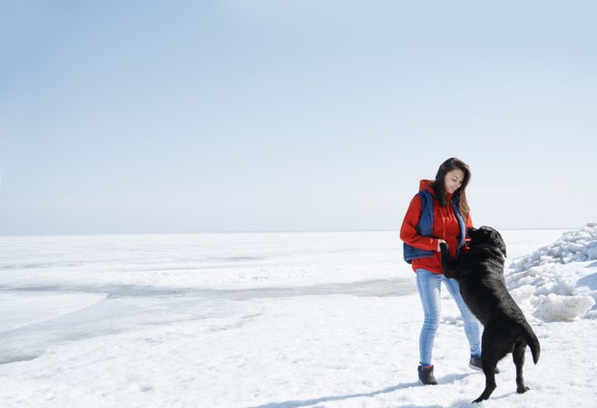 Young adult woman outdoors having fun with her dog in the ice