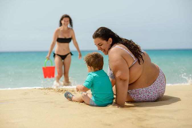 Mother and son playing with toys on sandy beach