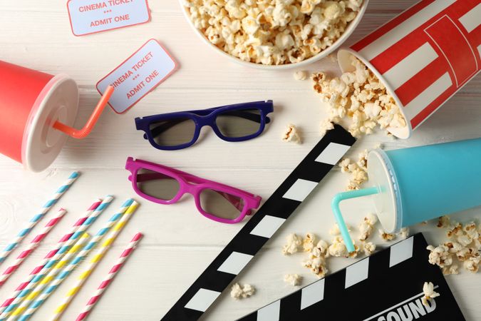 Flat lay. 3d glasses, buckets with popcorn, tickets, clapperboard, drink, on wood background