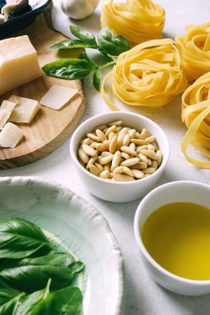 Basil leaves and ingredients for pesto sauce on plates on table