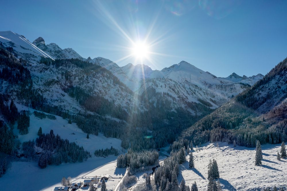 Winter sunny day in December, drone aerial view with snow covered pine forest and mountain peaks