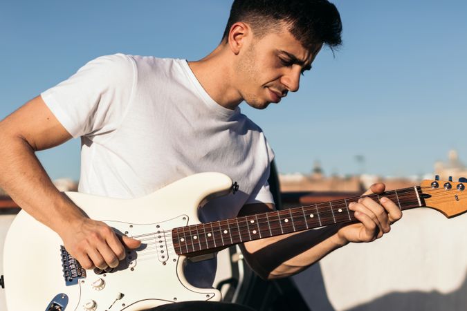 man playing electric guitar on a rooftop