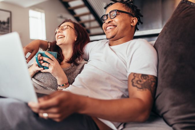 Smiling man and woman sitting on couch at home