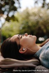 Woman relaxing outdoors listening to music with earphones bERan0