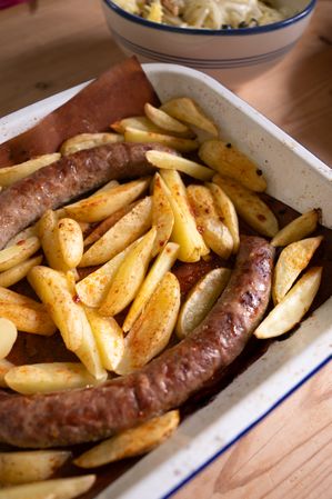 A dish with baked sausages and potatoes, fresh salad