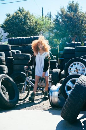 Full length fashion photo of young woman with natural hair outside at tire shop