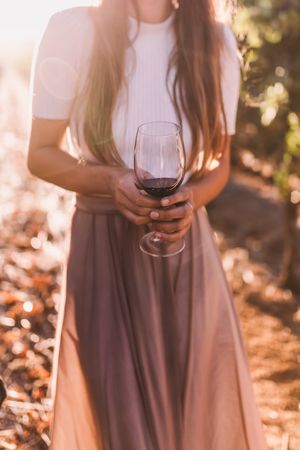 Young woman holding a glass of red wine outdoors