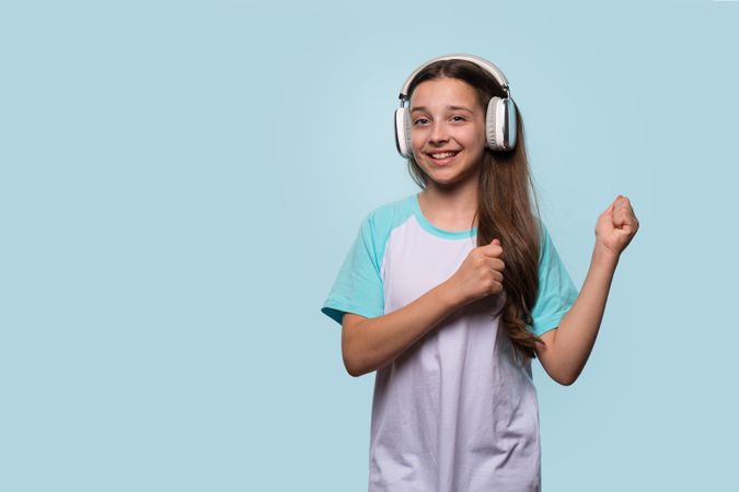 Girl smiling while dancing and enjoying music with headphones.