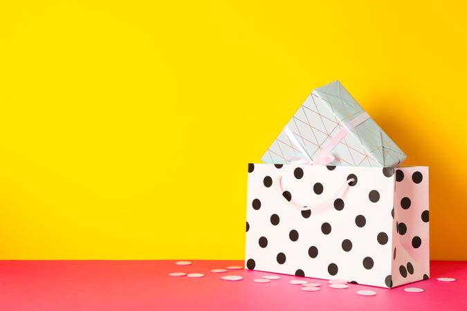 Paper bag with present on multicolor background, space for text