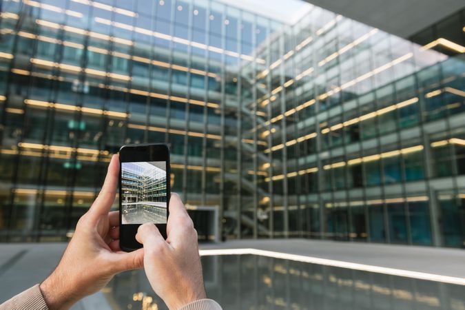 Man shooting building facade with smartphone in downtown