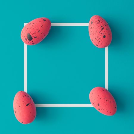 Bright pink Easter eggs on bright blue background with light frame