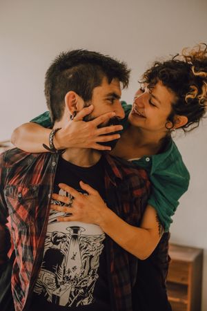 Loving hipster couple kissing and cuddling at home