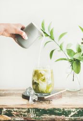Iced matcha drink with hand pouring cream