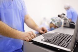 Male in scrubs at computer