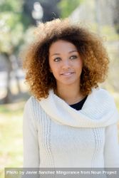 Female in sweater standing outside in park with selective focus 0WWjW0