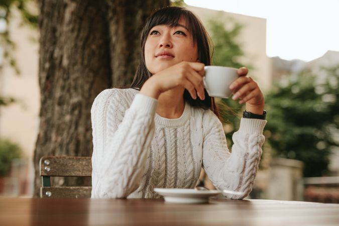 Young woman holding a cup of tea and looking away