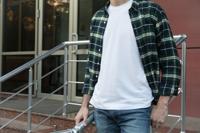 Men in t-shirt and checkered shirt against building, copy space