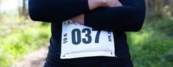 Unrecognizable female trail athlete posing with race number