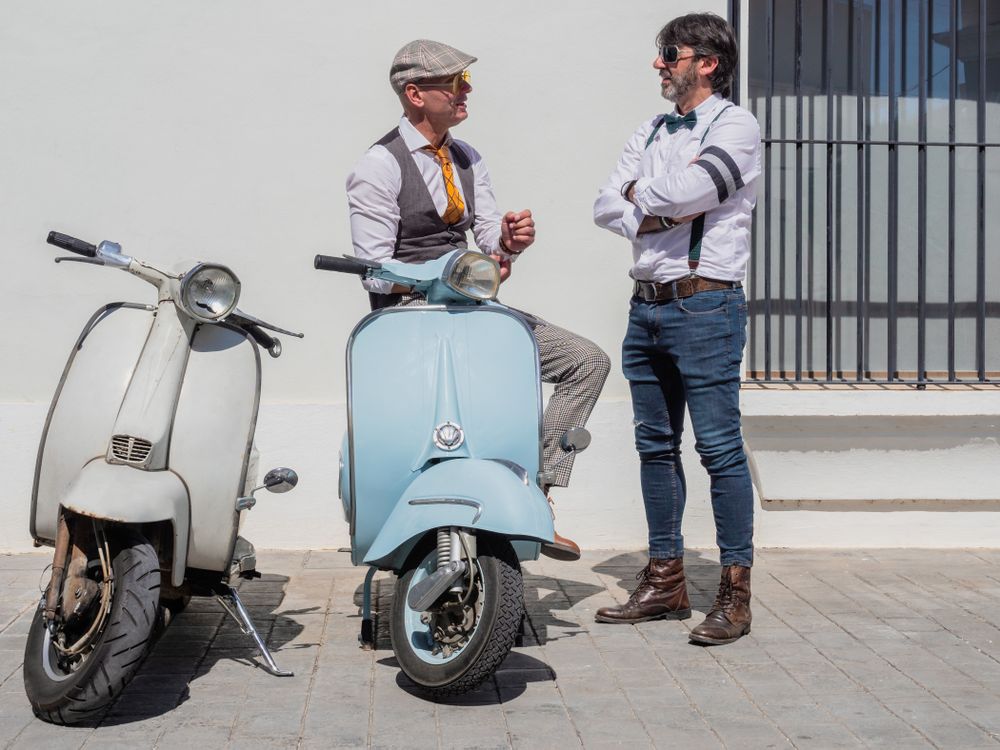 Trendy men chatting near vintage scooters