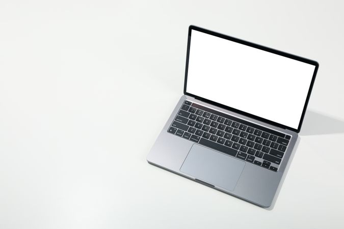 Opened silver laptop at angle with mockup screen on desk with copy space