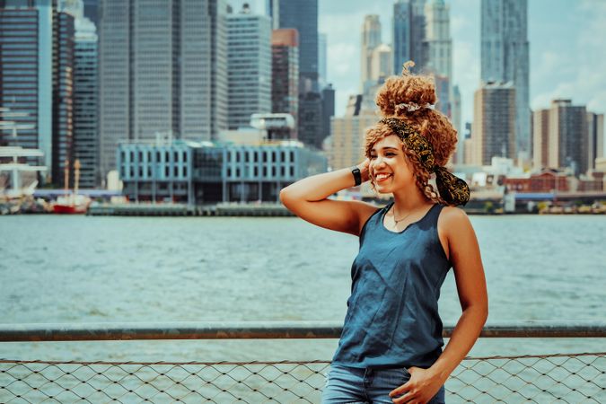 Black woman smiling with her hand to her hair with Hudson River in the background, copy space