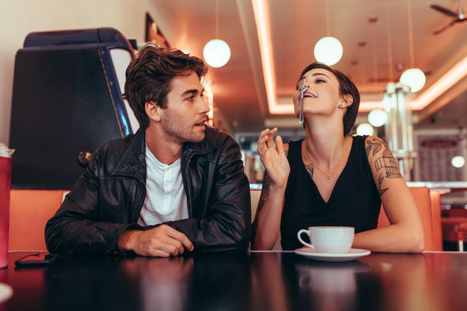 Couple sitting at a restaurant with a coffee on the table and having fun