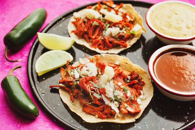Pepper and lime near tacos al pastor and sauces