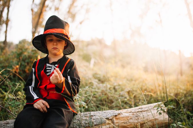 Boy in skeleton costume sitting on log