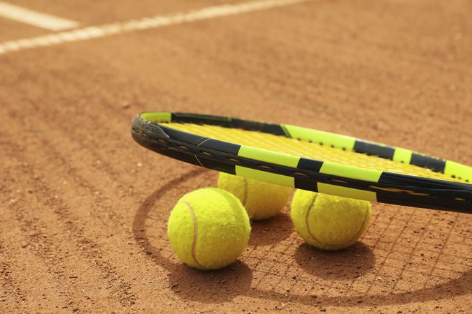 Racket and tennis balls on clay court