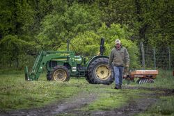 Copake, New York - May 19, 2022: Farmer walking away from tractor in field 5pX8g5