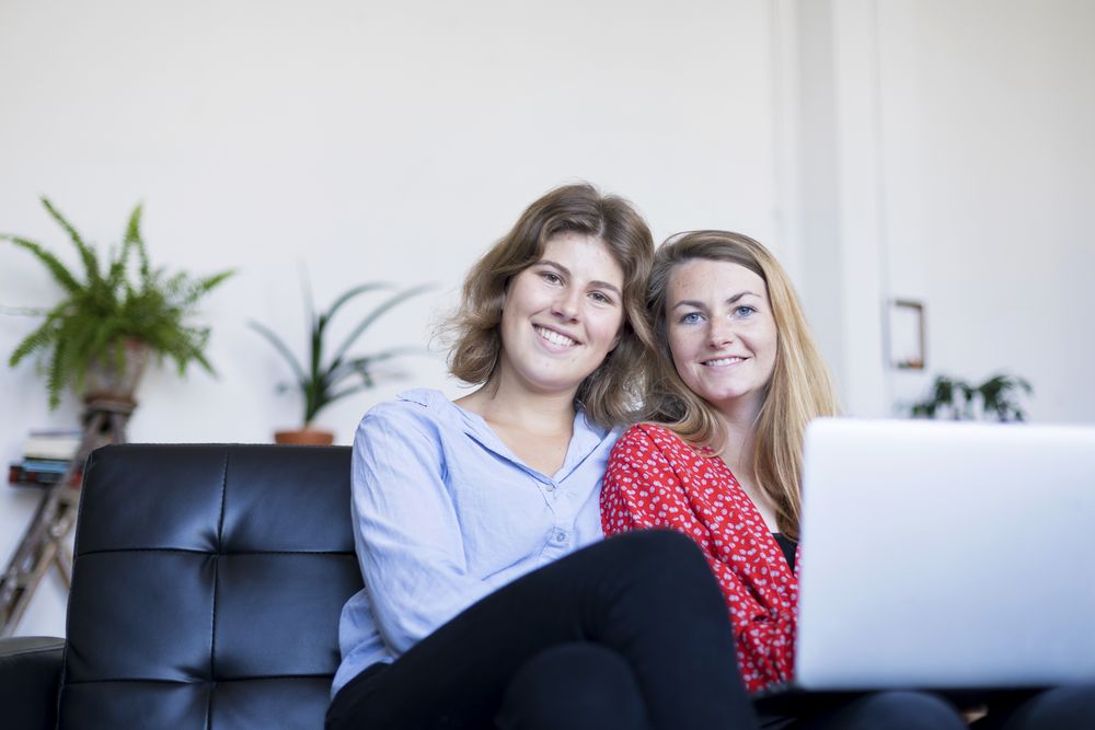 Happy couple using computer while sitting on couch