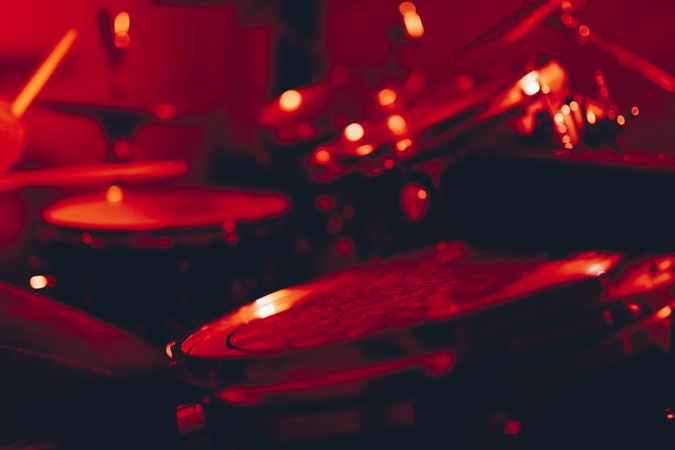 Man with drumsticks playing on drums in redness