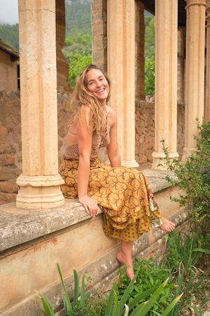 Happy woman sitting near old stone building