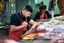 Butchers working behind counter with meat bGZvY4