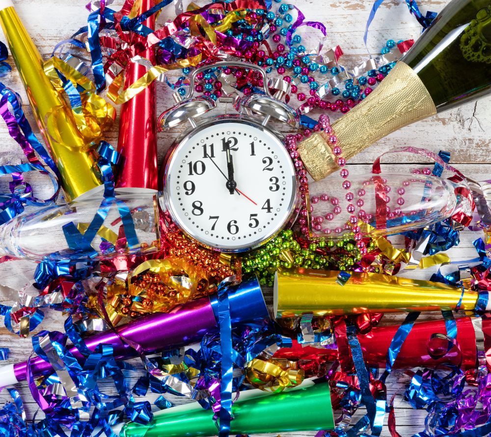 Happy New Year Celebration with clock in center of party objects on rustic wooden boards