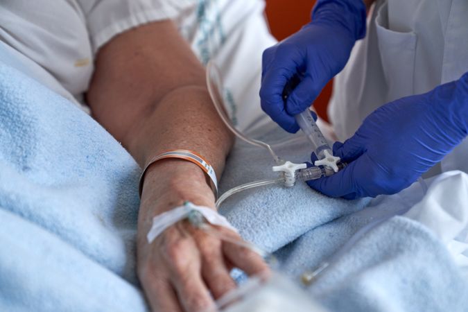 Crop nurse injecting patient with drug intravenously