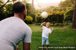 Father and son playing with a football in backyard garden 4NZ9D4