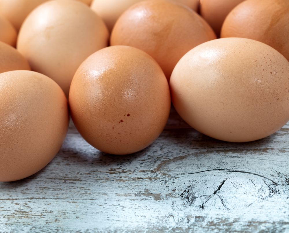 Raw organic brown farm eggs on rustic wood background