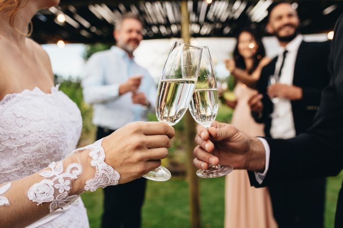 Newlyweds clinking glasses at wedding reception outside