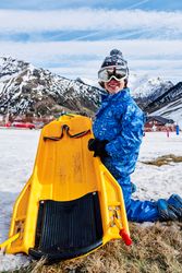 Happy child with sledge on ski resort