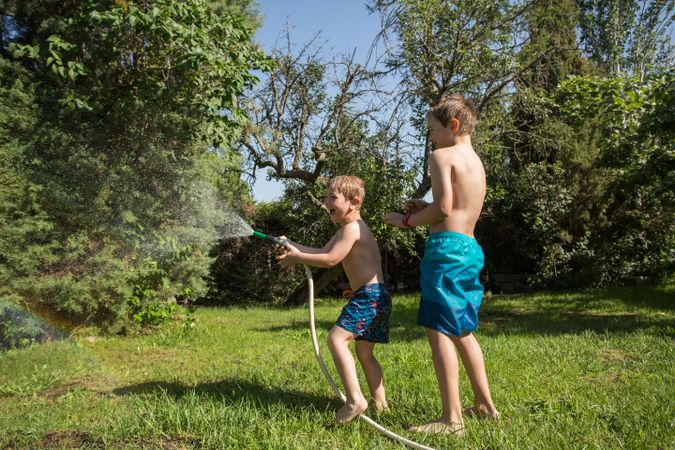 Little kids in swimwear having fun with splashing water