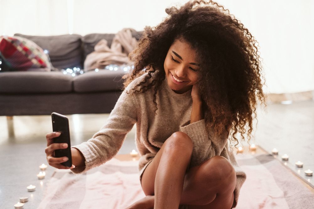Black woman taking selfie on floor