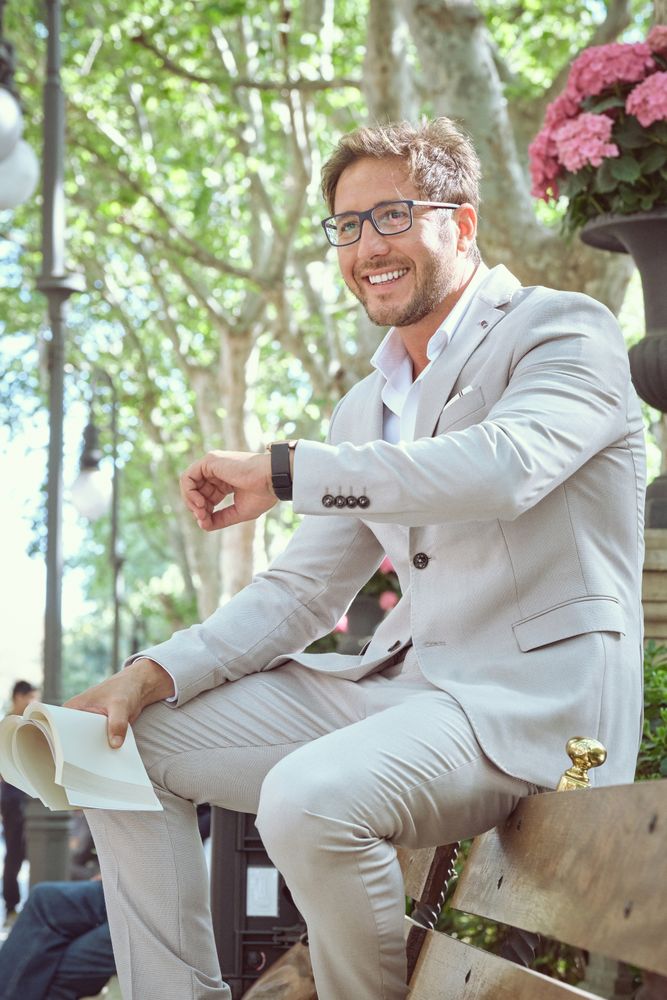 Cheerful elegant businessman with book in hand waiting for meeti