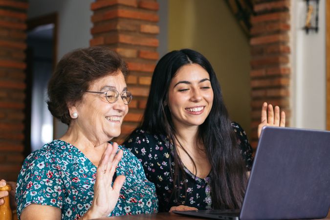 Grandmother and granddaughter making video call with laptop at home