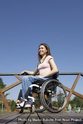Happy woman in a wheelchair on a bridge, vertical 4OABZ0