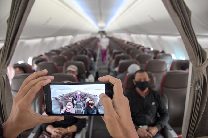 Person taking a photo of airplane passengers with facemasks